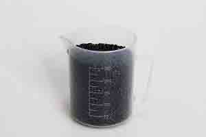 Beaker of plastic masterbatch pellets for injection molding at Michigan CNC Machining Parts, Inc.